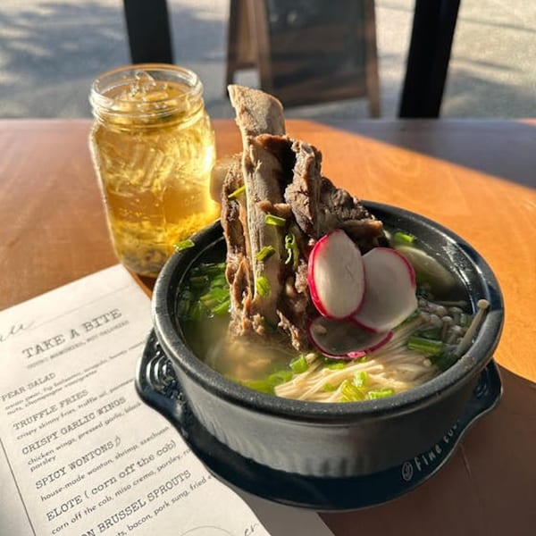 Vietnamese bone marrow pho with radishes and enoki mushrooms, alongside a drink and menu.