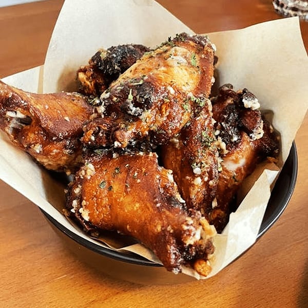Crispy Vietnamese chicken wings, seasoned with garlic and herbs, served in a black bowl lined with parchment paper.